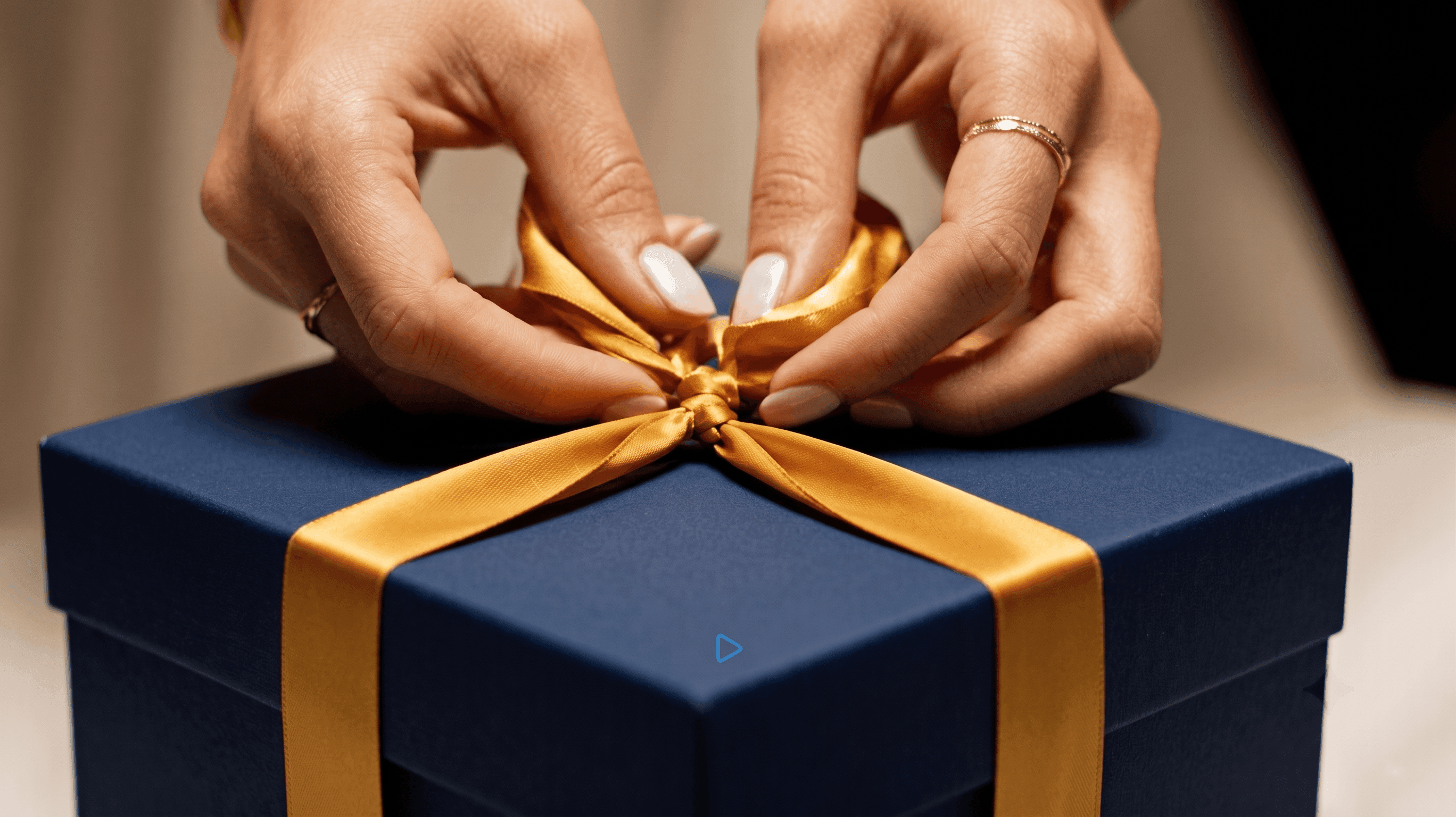 Hands tying a ribbon on a gift box
